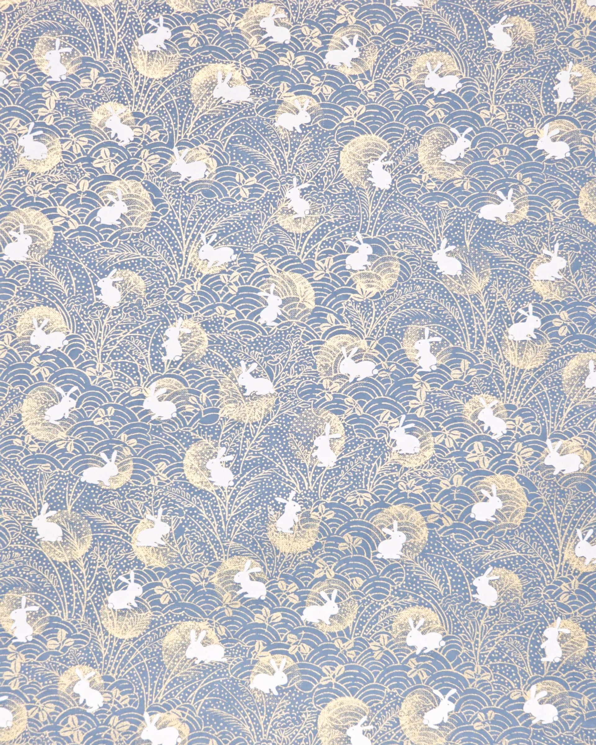 Japanese chiyogami featuring white rabbits with gold moons on a blue gray background with metallic gold accents.