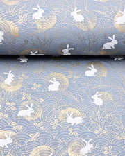 Japanese chiyogami featuring white rabbits with gold moons on a blue gray background with metallic gold accents.