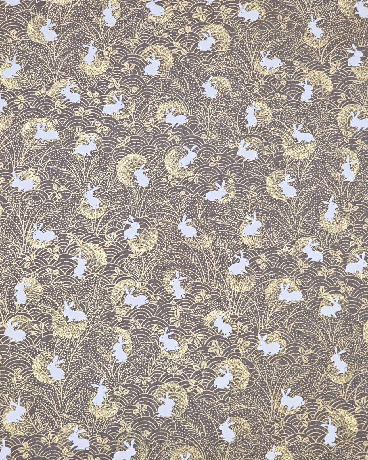 Japanese chiyogami paper featuring white rabbits with gold moons on a brown background with metallic gold accents.