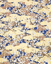 Japanese chiyogami paper featuring white plum blossom branches with red swirls on a blue and gold background with metallic gold accents.