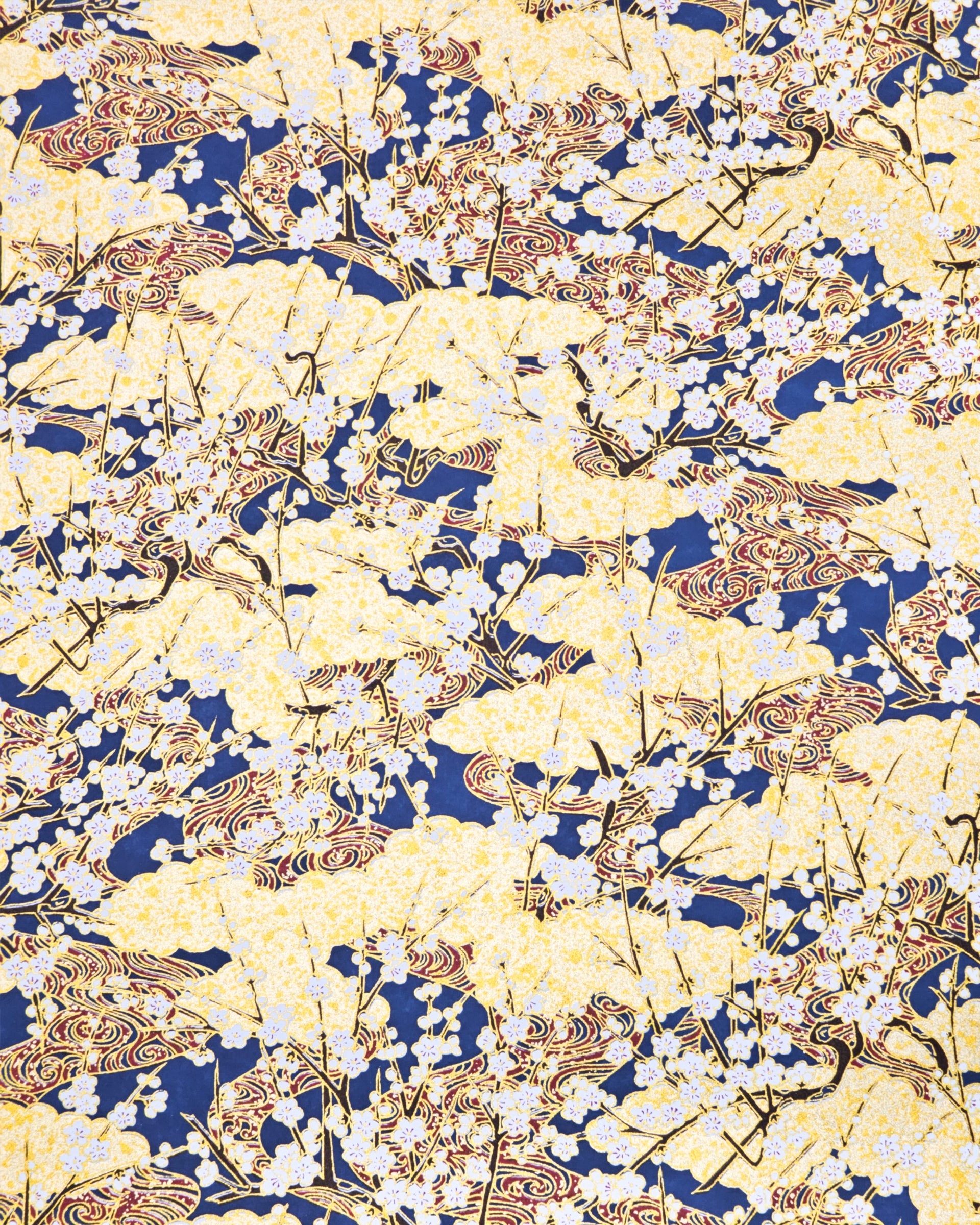 Japanese chiyogami paper featuring white plum blossom branches with red swirls on a blue and gold background with metallic gold accents.