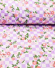 Japanese chiyogami paper featuring pink, red, and white flowers on a purple ichimatsu (checkered) background with metallic gold accents.