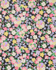 Japanese chiyogami paper featuring pink, yellow, purple, and white cherry blossoms and purple yukiwas on a black background with metallic gold accents.