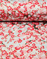 Japanese chiyogami paper featuring a red plum blossom tree with a dark brown tree trunk on a metallic silver background with metallic gold accents.