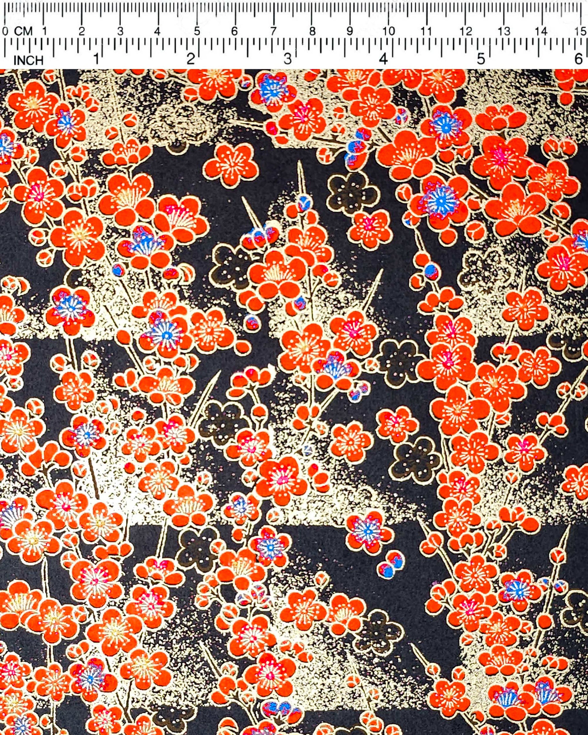 Japanese chiyogami featuring red plum blossoms with a little bit of blue on a black background with metallic gold accents.