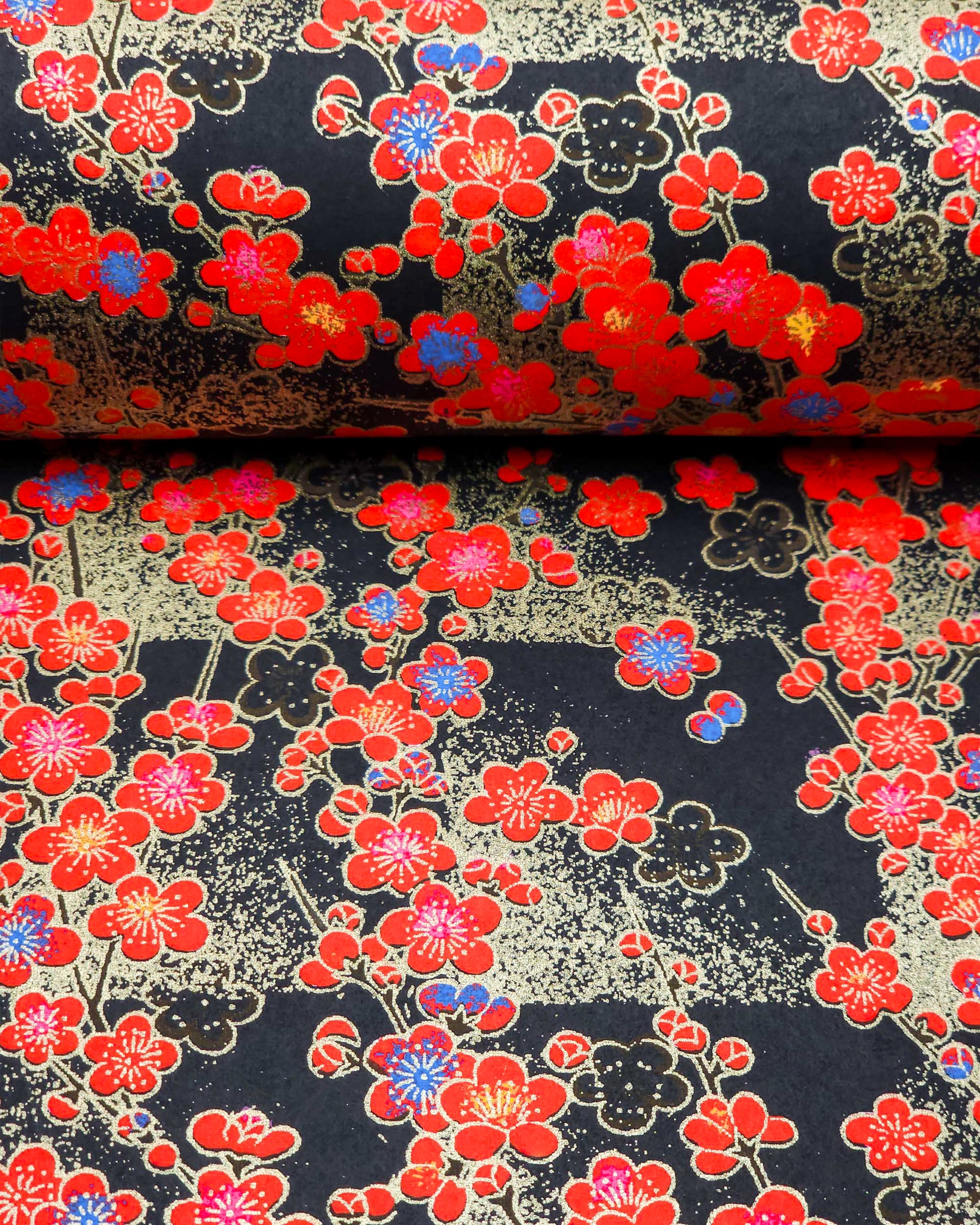 Japanese chiyogami featuring red plum blossoms with a little bit of blue on a black background with metallic gold accents.