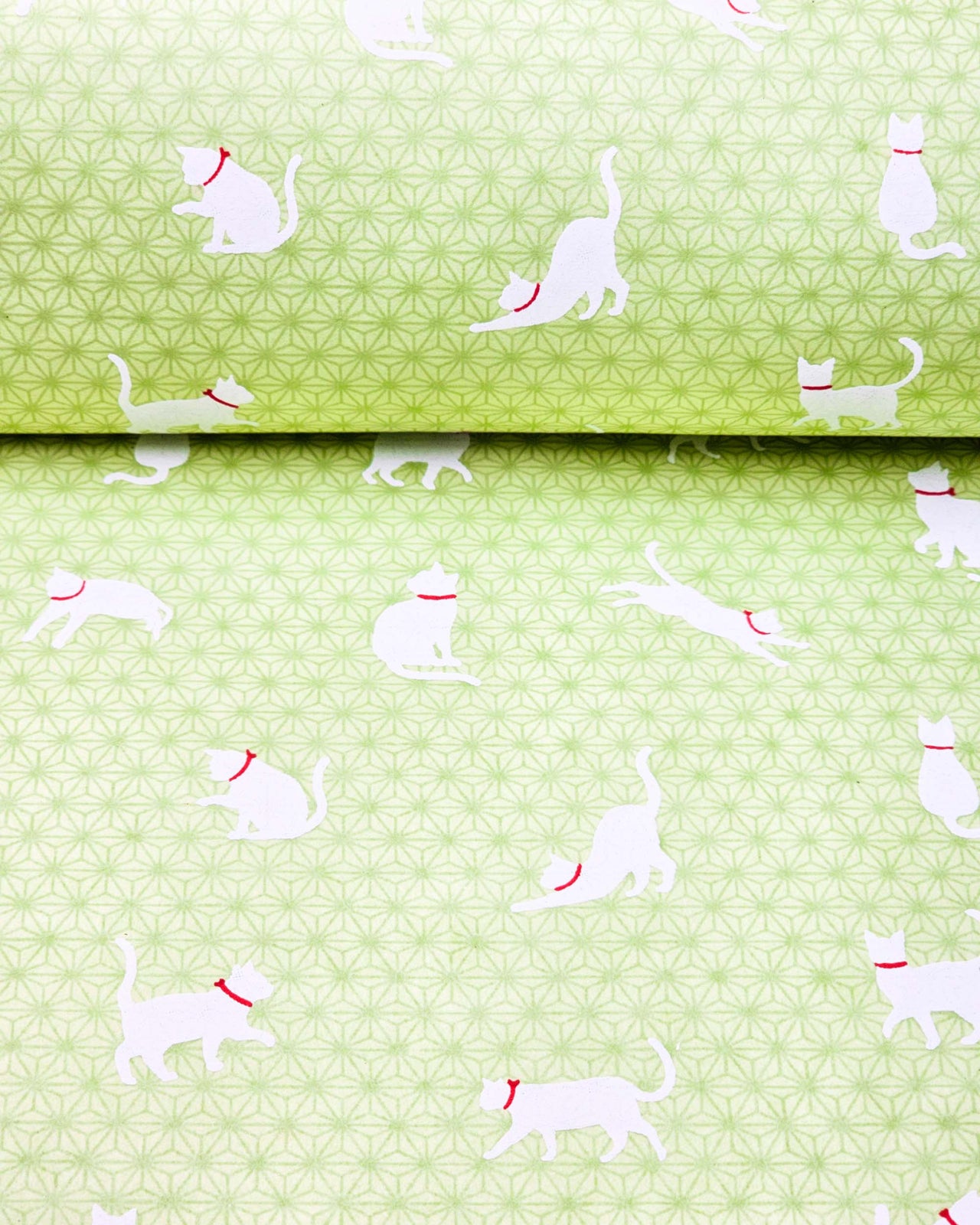 Japanese chiyogami featuring white cats with red collars on a green asanoha (hemp leaf) background.