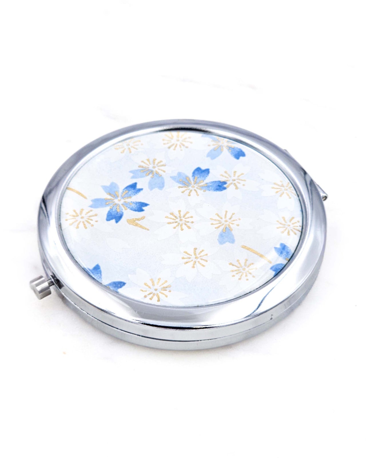 Silver metal compact mirror featuring white and blue cherry blossoms on a light white and blue background with metallic gold accents.
