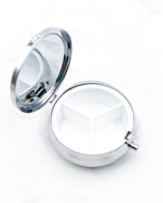 Opened silver metal pill box showing 3 compartments