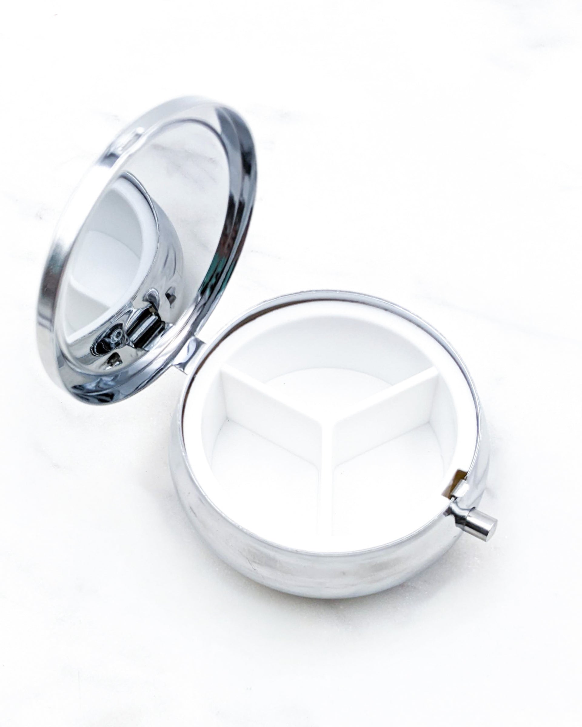 Opened silver metal pill box showing 3 compartments