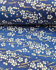 Japanese chiyogami featuring small white plum blossoms & matsuba (pine needles) on a blue background with metallic gold accents.