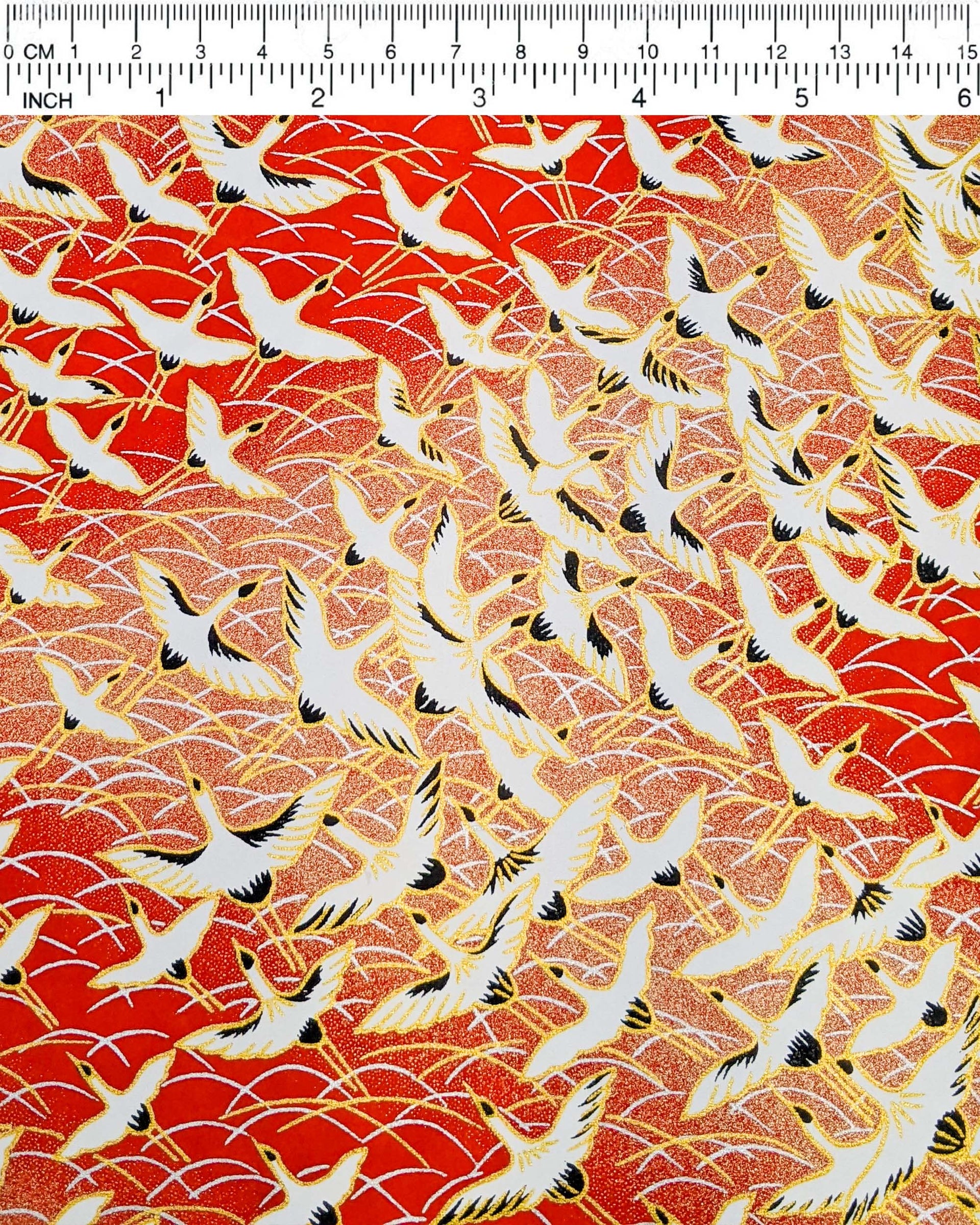 Japanese chiyogami featuring flying white cranes zigzagging on a gold & red background with metallic gold accents.