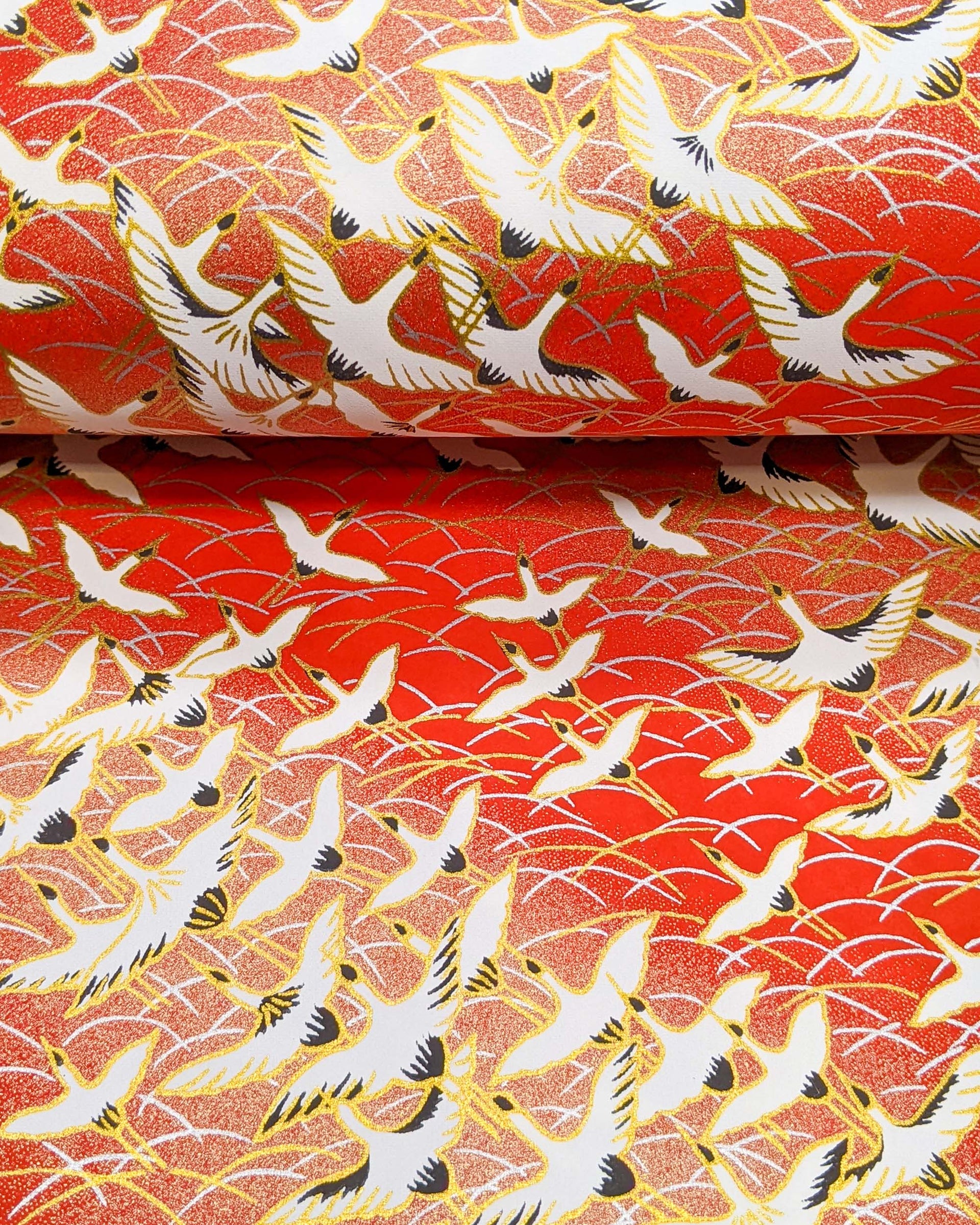 Japanese chiyogami featuring flying white cranes zigzagging on a gold & red background with metallic gold accents.