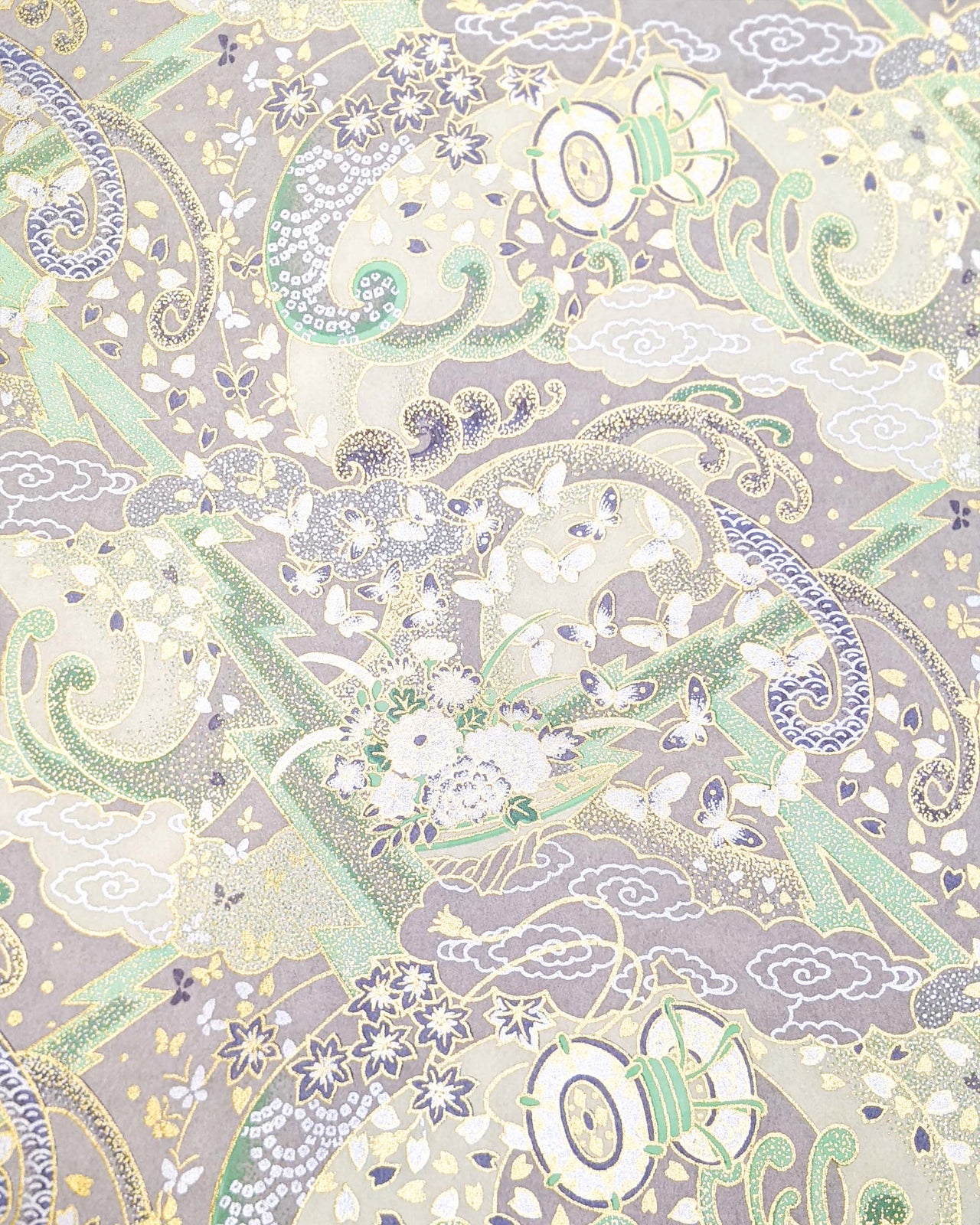Japanese chiyogami paper featuring a light gray and turquoise stormy seascape with lightning, butterflies, and floral boats with metallic gold and silver accents.