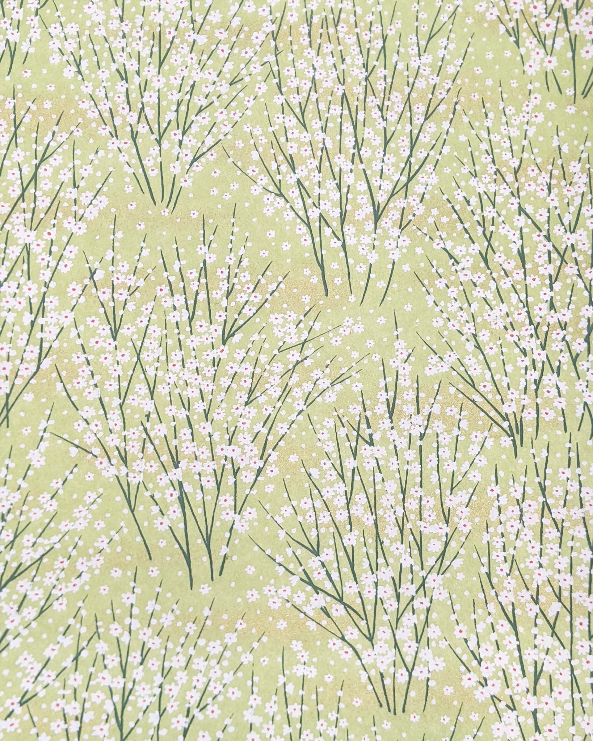 Japanese chiyogami paper featuring small white flower bushes over a yellow green background with metallic gold accents.