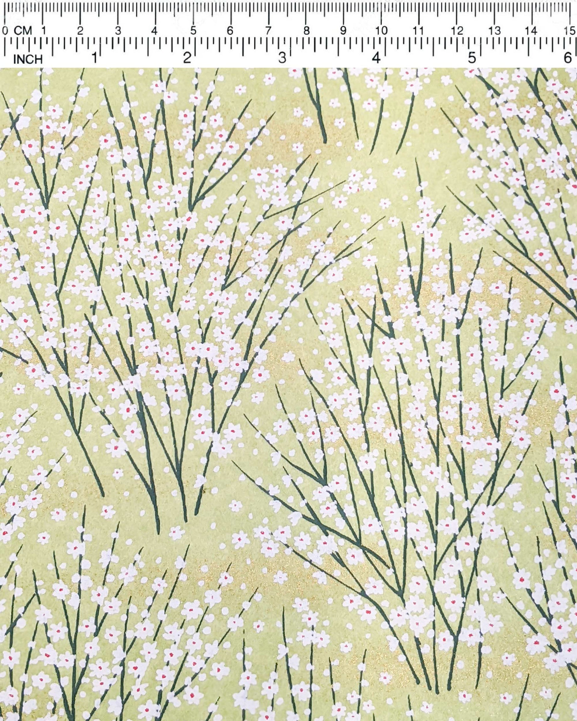 Japanese chiyogami paper featuring small white flower bushes over a yellow green background with metallic gold accents.