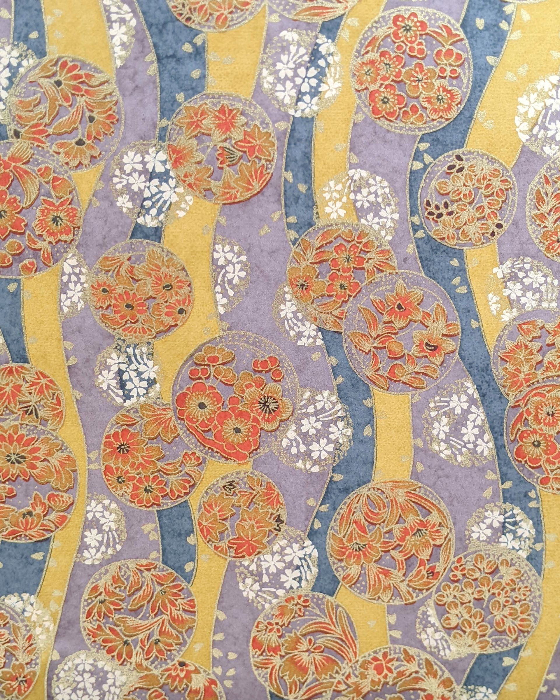 Japanese chiyogami paper featuring purple & orange floral temari balls on a blue, purple, and light orange background with metallic gold accents.