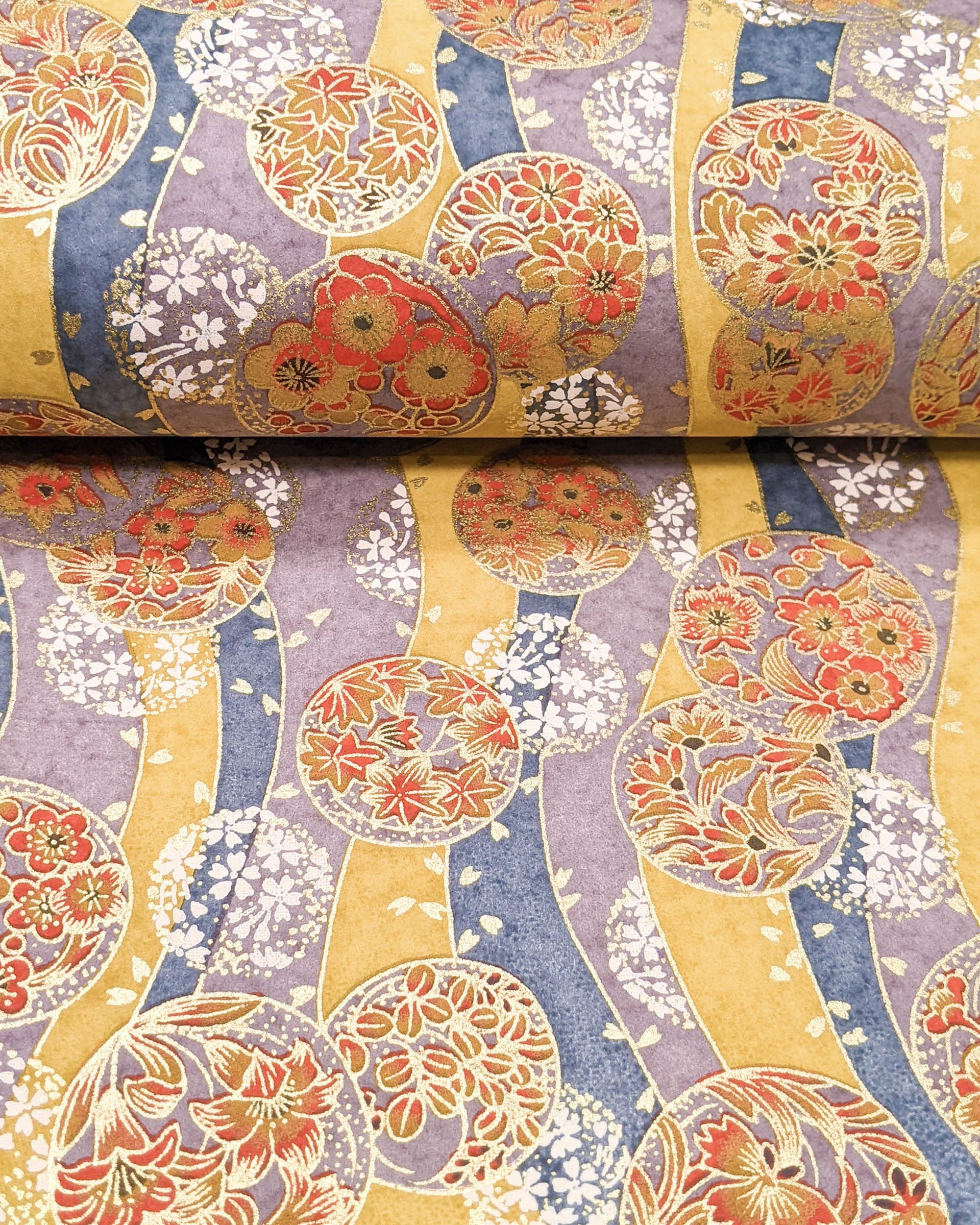Japanese chiyogami paper featuring purple & orange floral temari balls on a blue, purple, and light orange background with metallic gold accents.