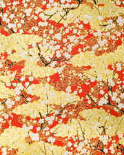 Japanese chiyogami featuring white plum blossom branches on a red and gold background with metallic gold accents.