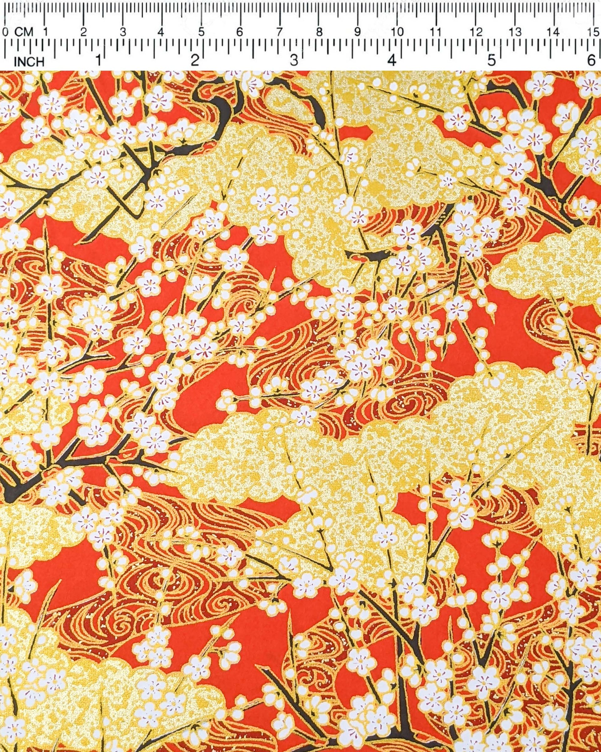 Japanese chiyogami featuring white plum blossom branches on a red and gold background with metallic gold accents.