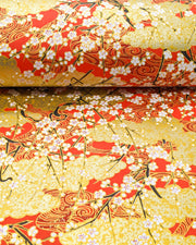 Japanese chiyogami featuring white plum blossom branches on a red and gold background with metallic gold accents.