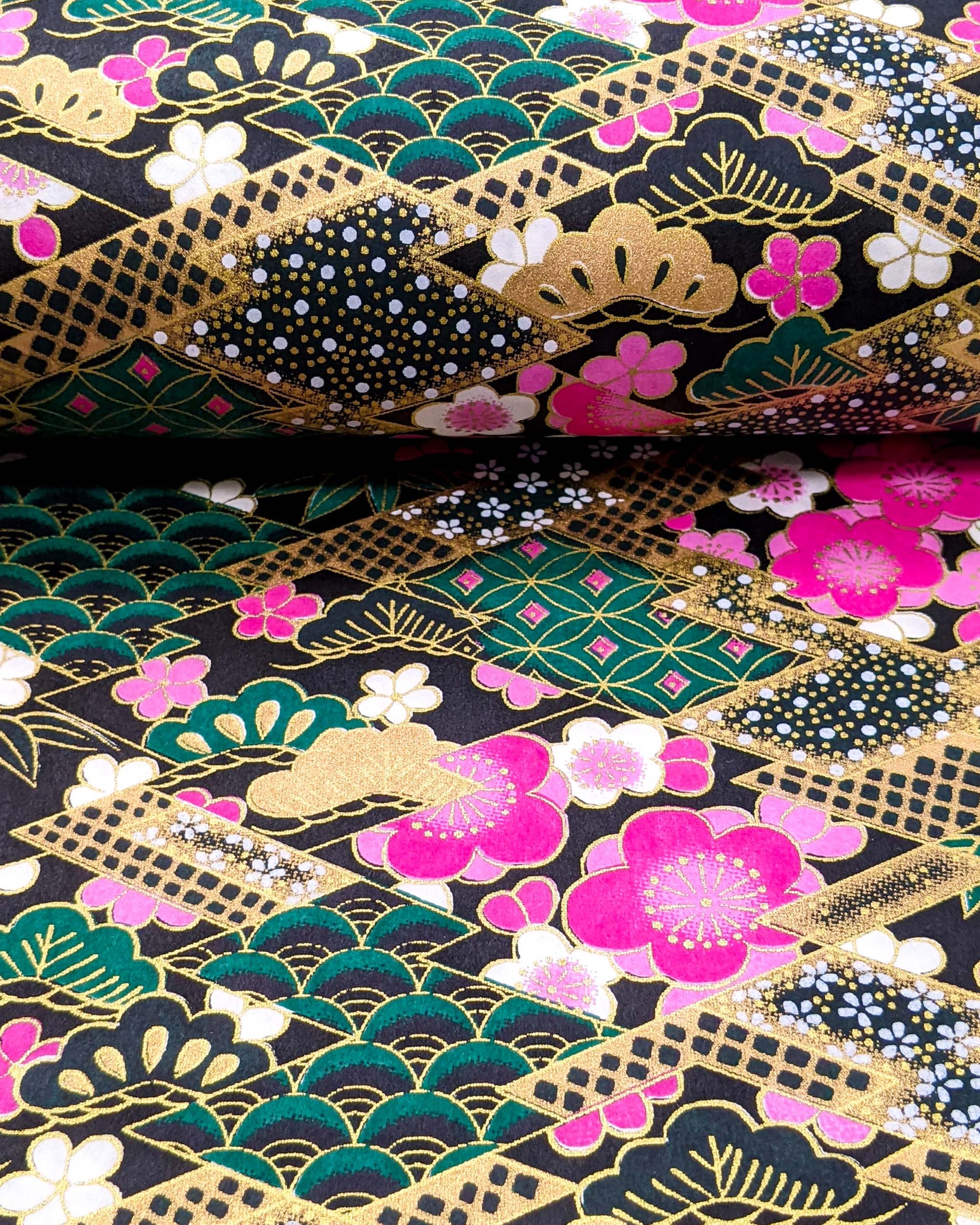 Japanese chiyogami paper featuring pink & white plum blossoms on a black & green background with metallic gold accents.