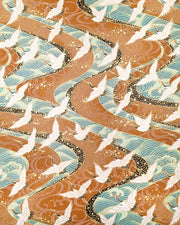 Japanese chiyogami paper featuring cranes flying over turquoise colored rivers on a brown background with metallic gold accents.