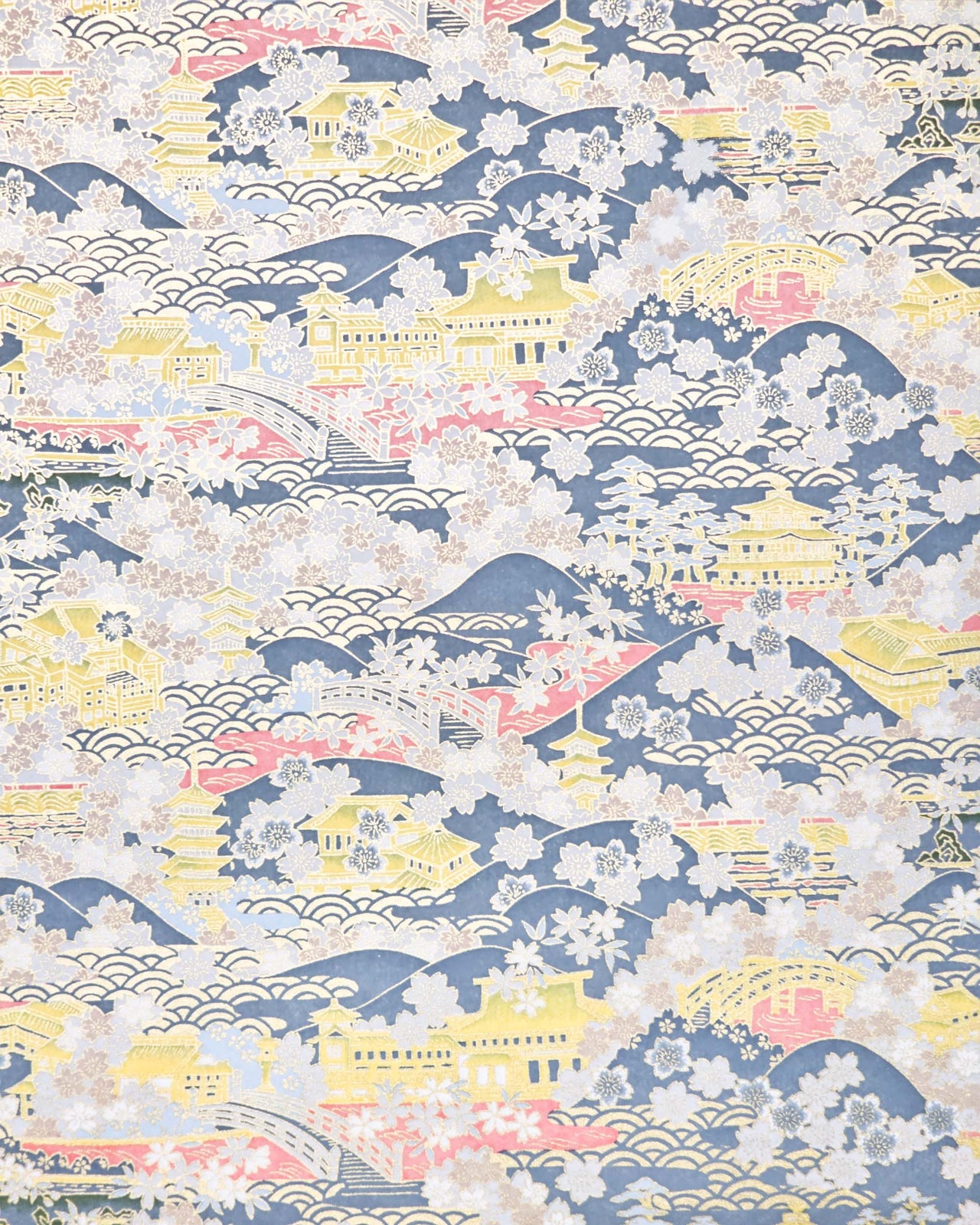 Japanese chiyogami paper featuring a village scene with yellow pagodas, buildings, and bridges with pink water, light gray cherry blossoms on a blue gray background with metallic gold accents