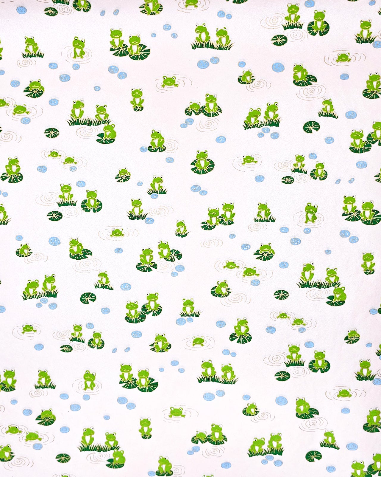 Japanese chiyogami featuring green frogs sitting on green lily pads on a pearlescent pink background with metallic gold accents.