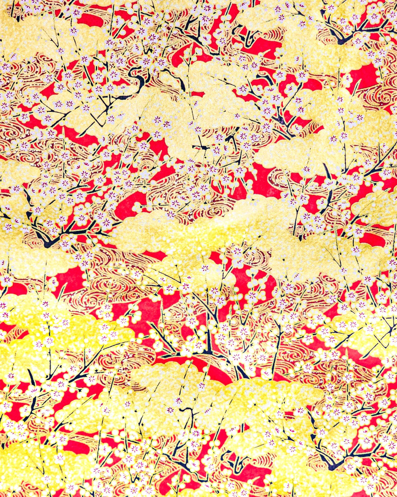 Japanese chiyogami featuring white plum blossom branches on a red and gold background with metallic gold accents.