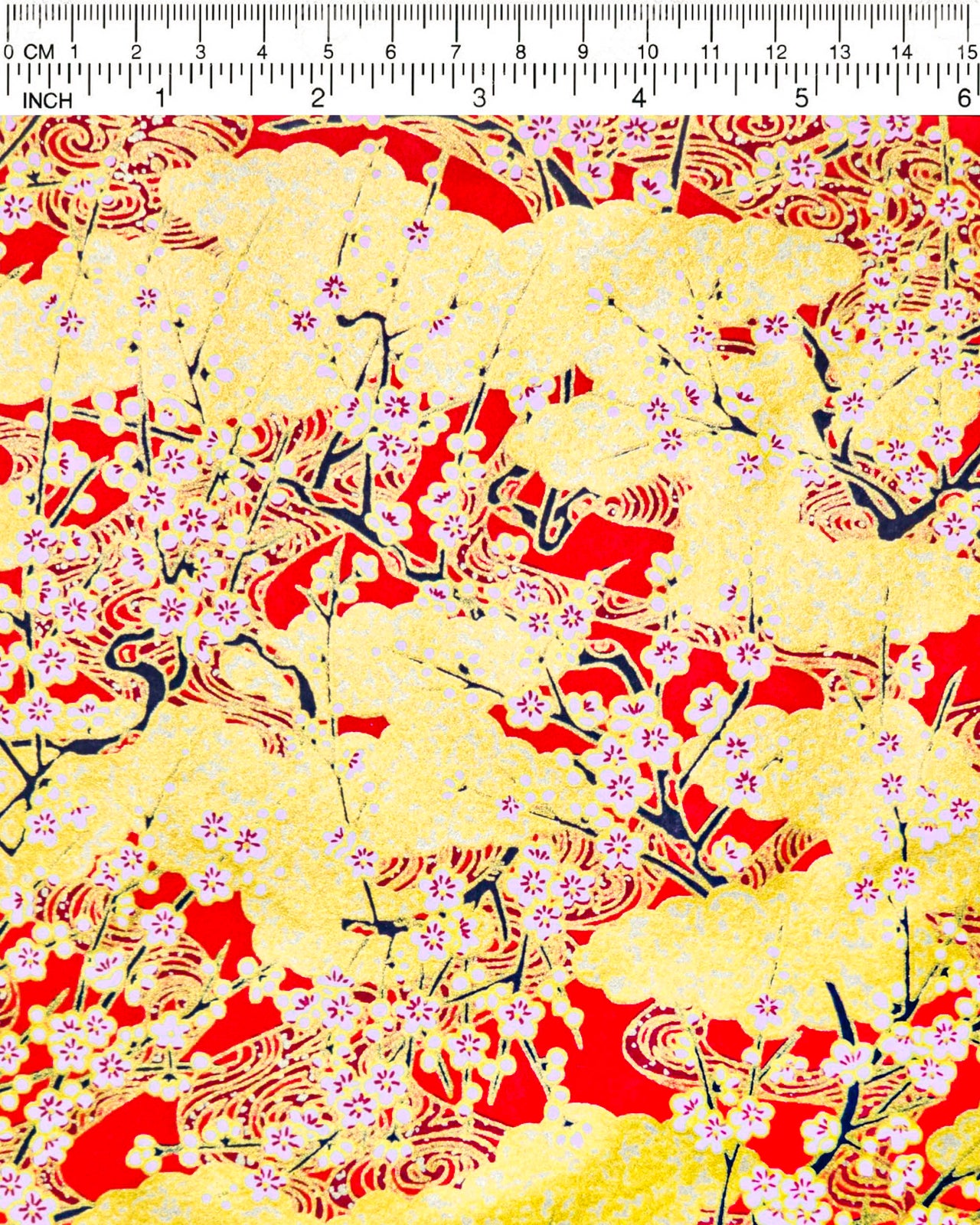 Japanese chiyogami featuring white plum blossom branches on a red and gold background with metallic gold accents.