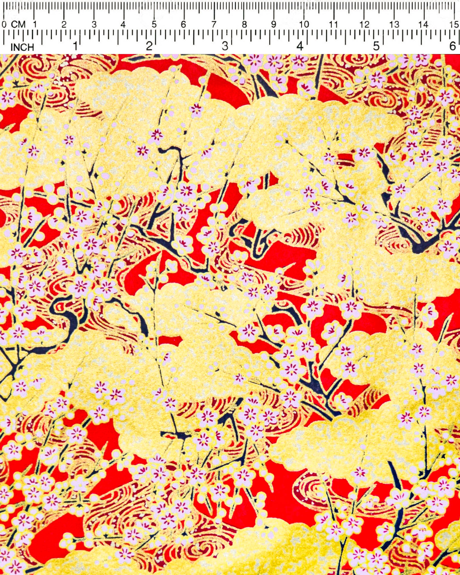 Japanese chiyogami featuring white plum blossom branches on a red and gold background with metallic gold accents.