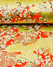 Japanese chiyogami featuring white plum blossom branches on a red and gold background with metallic gold accents.