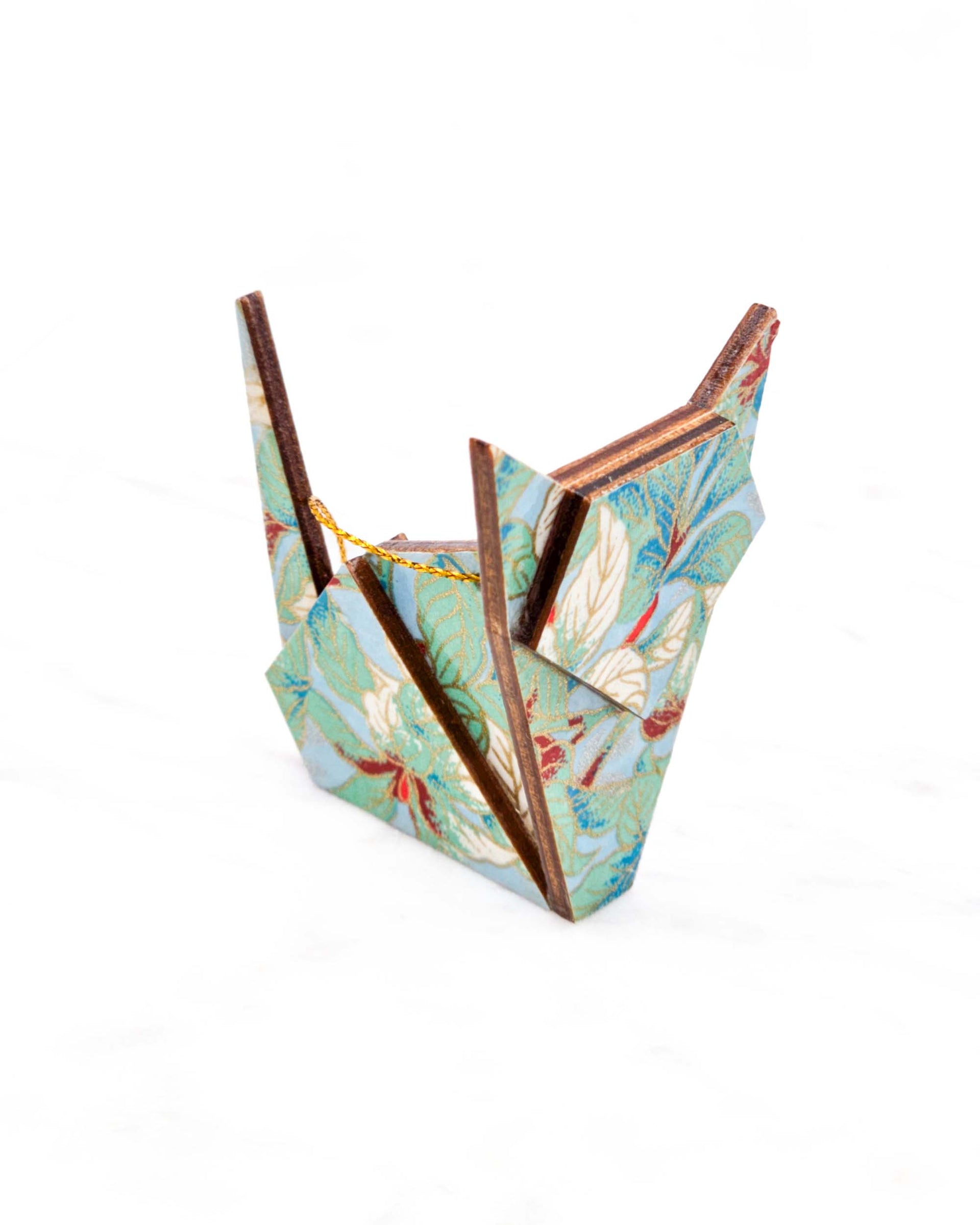 Small wooden origami cat ornament featuring green, white, red, and silver leaves on a light blue background with metallic gold details.