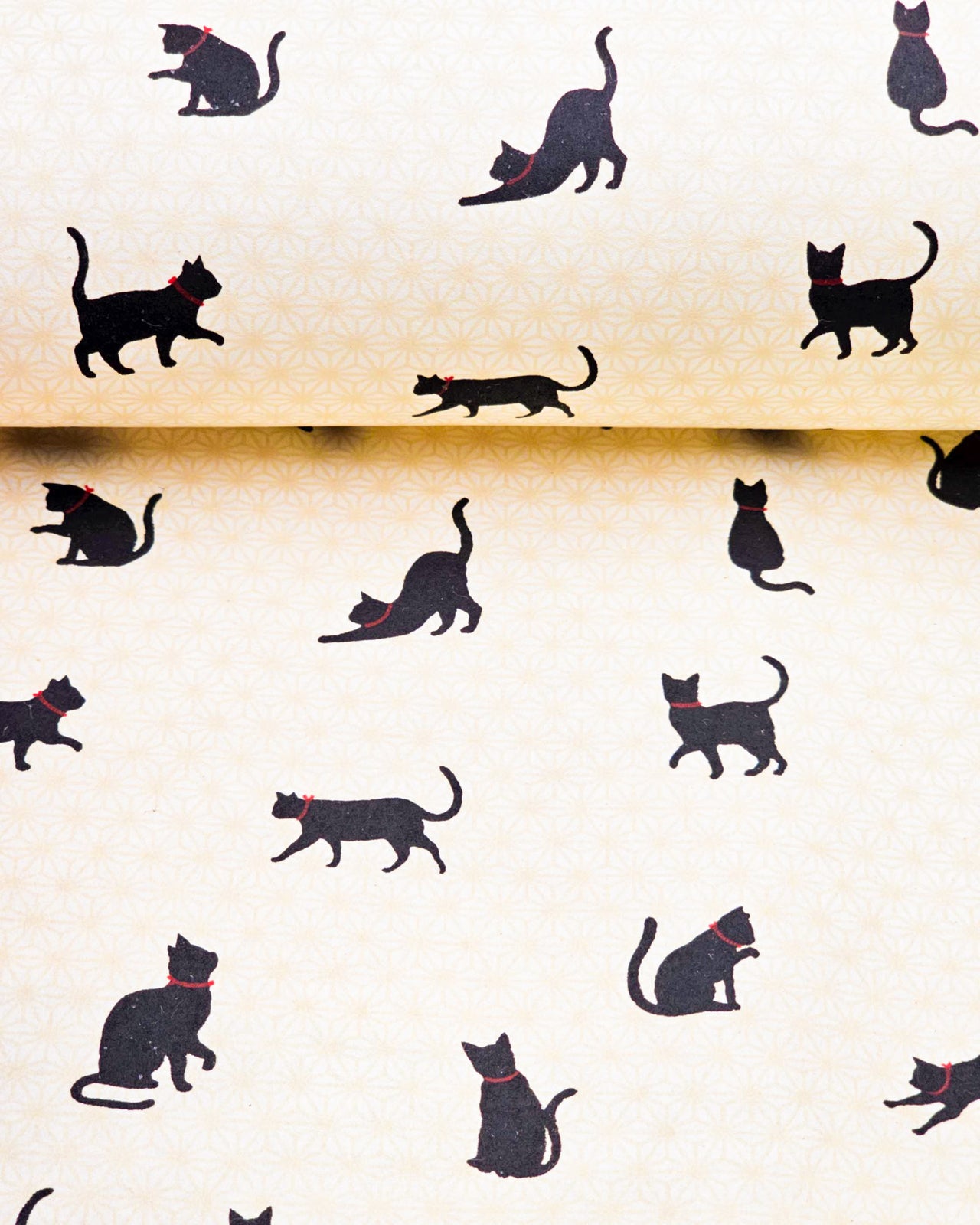 Japanese chiyogami paper featuring black cats with red collars on a beige asanoha (hemp leaf) background.