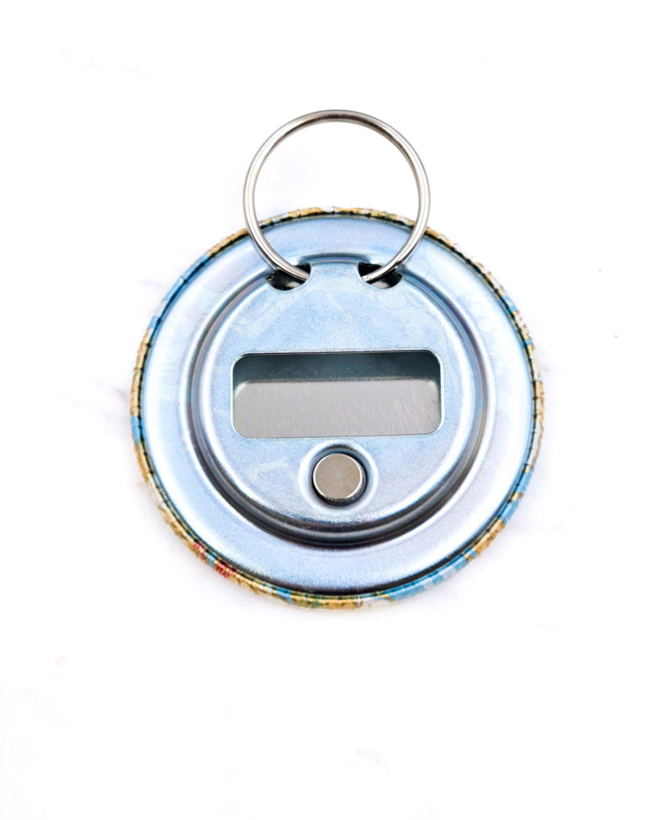 Magnetic bottle opener featuring beige leaves on a light blue background with metallic gold accents.