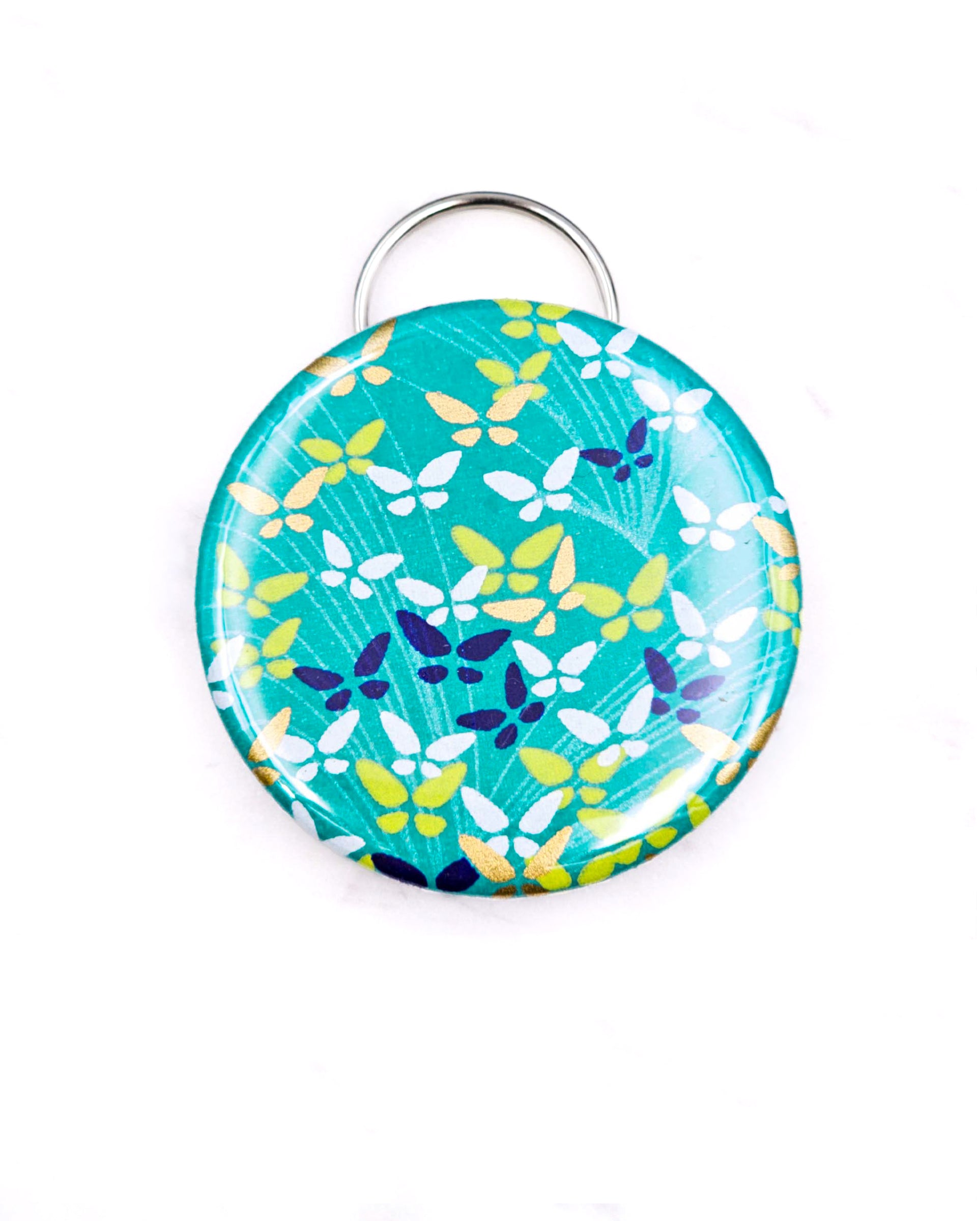 Magnetic bottle opener featuring small butterflies on a green background with metallic gold accents.