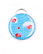 Magnetic bottle opener featuring red fishes and white dots on a blue background with metallic gold accents.
