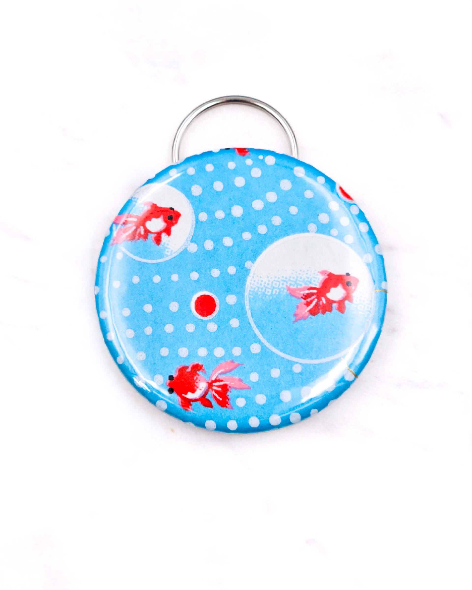 Magnetic bottle opener featuring red fishes and white dots on a blue background with metallic gold accents.