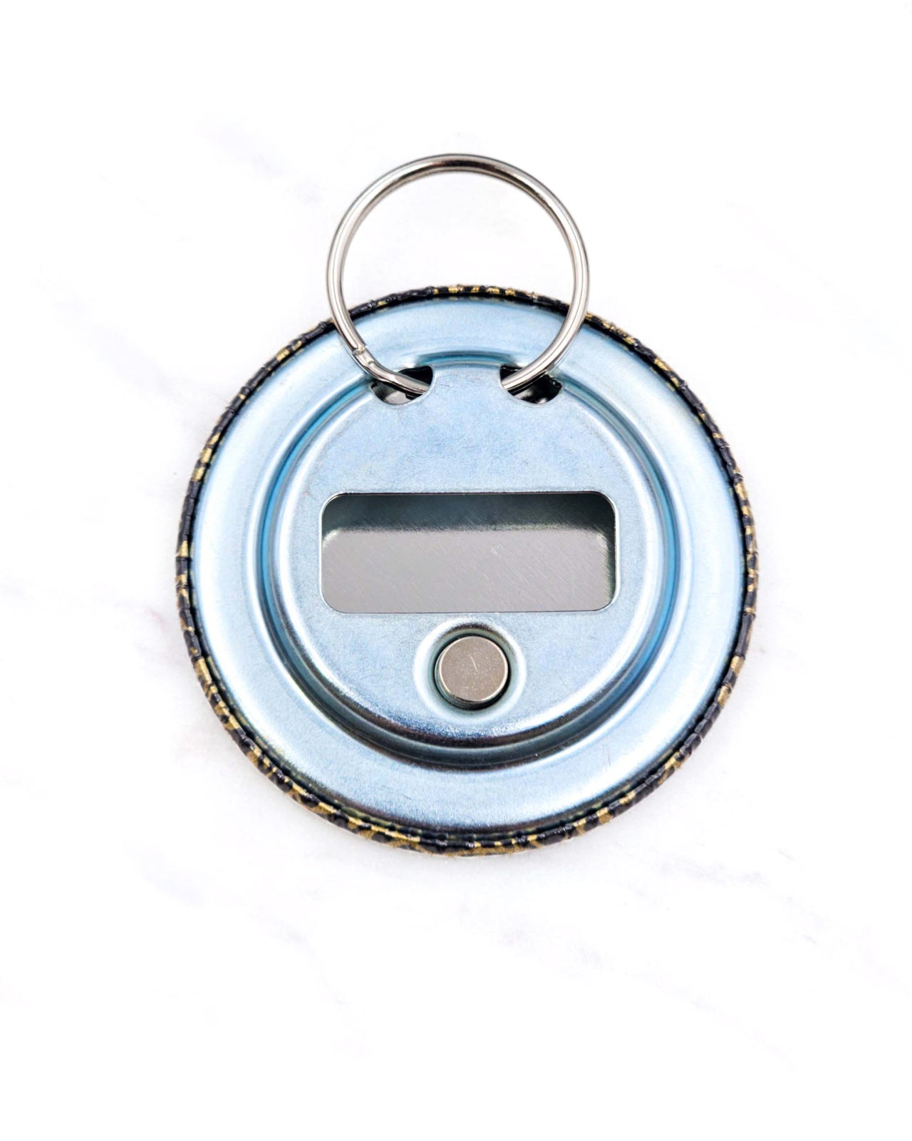 Magnetic bottle opener featuring a metallic gold floral design on a black background.