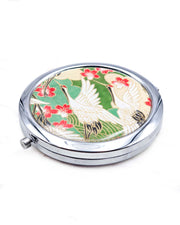 Round silver metal compact mirror featuring white flying cranes and red and white cherry blossoms on a green background with metallic gold details.