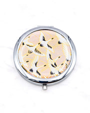Round silver metal compact mirror featuring white flying cranes on a light pink background with metallic gold accents.
