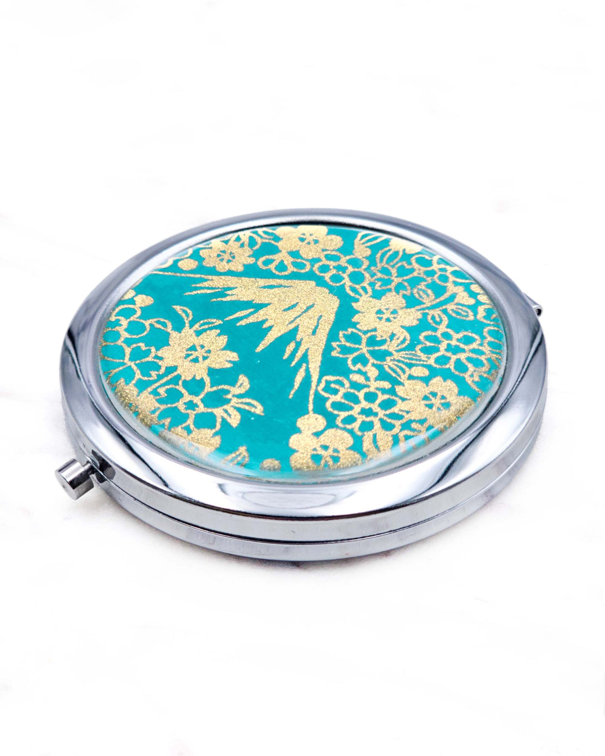 Round silver metal compact mirror featuring metallic gold Mt Fuji and cherry blossoms on a teal blue background.