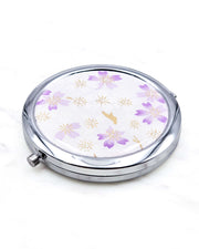 Round silver metal compact mirror featuring light purple and white cherry blossoms on a white background with metallic gold accents.