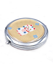 Round silver metal compact mirror featuring a white, red, and blue maneki-neko (lucky cat) with blue hanabishi (flower diamond) motifs on a metallic gold background.