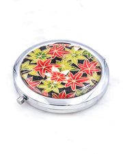 Silver metal compact mirror featuring green, red, and white maples leaves on a black background with metallic gold accents.