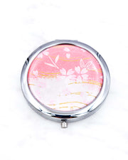 Silver metal compact mirror featuring pink cherry blossoms on a pink and white background with metallic gold accents.