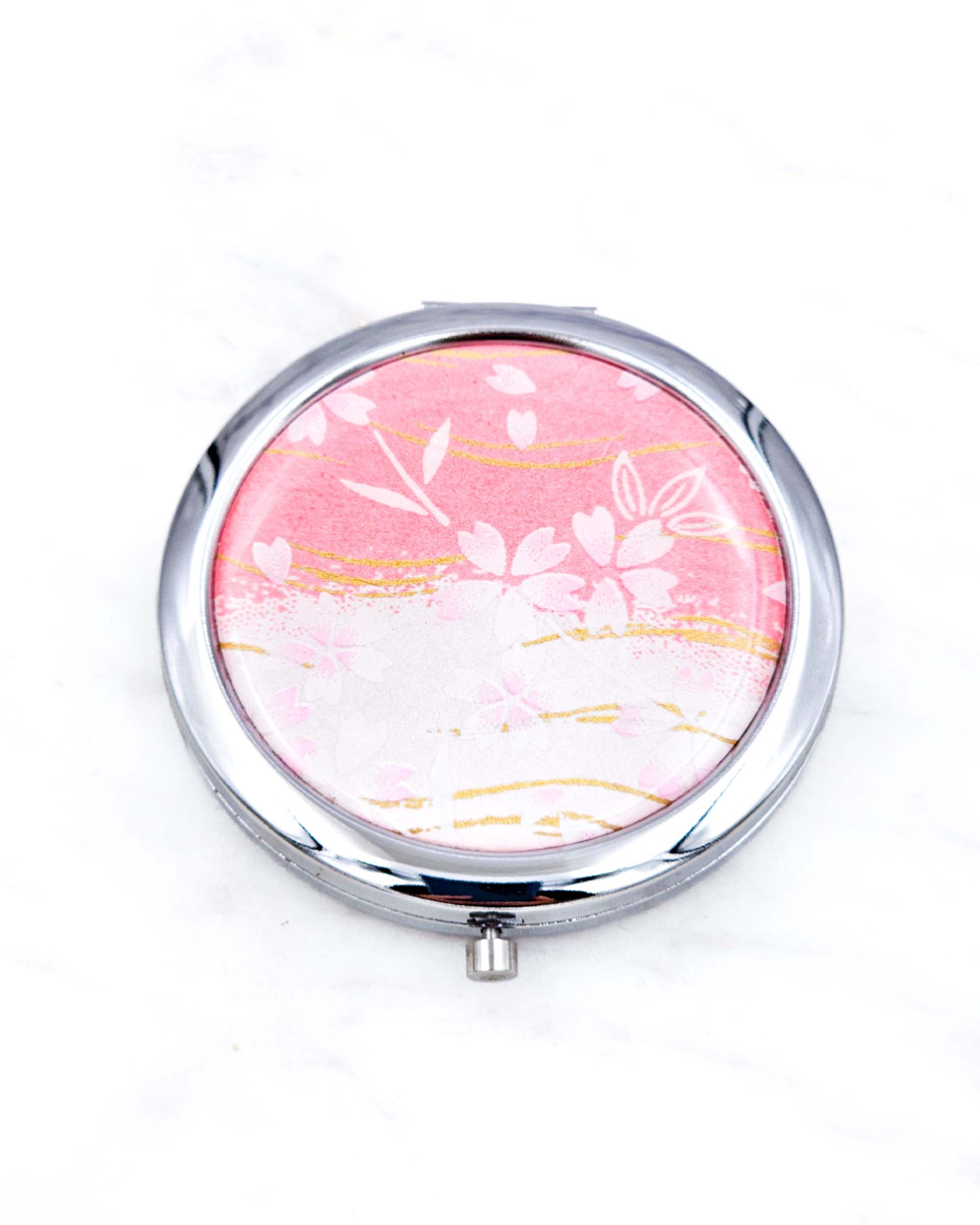 Silver metal compact mirror featuring pink cherry blossoms on a pink and white background with metallic gold accents.