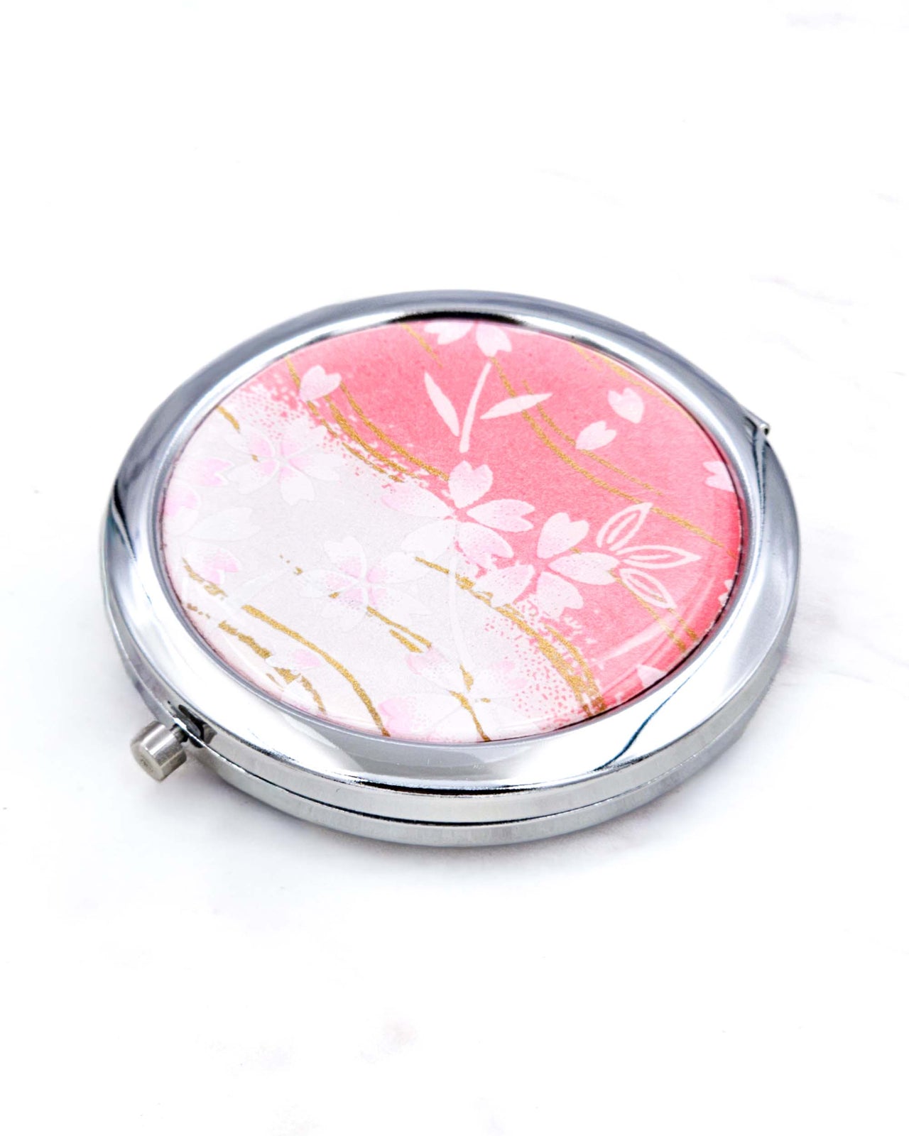 Silver metal compact mirror featuring pink cherry blossoms on a pink and white background with metallic gold accents.