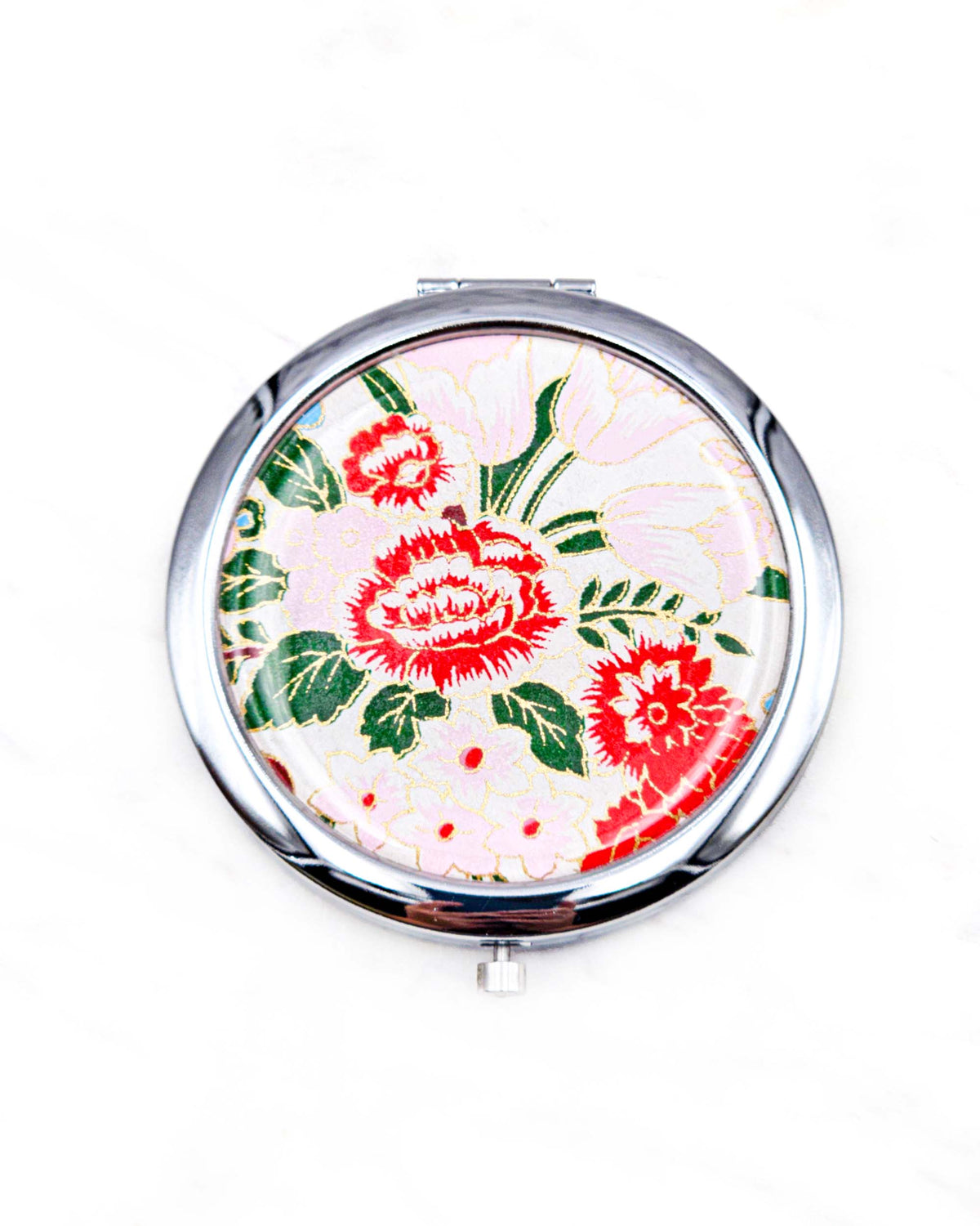 Round silver metal compact mirror featuring red and white peonies, soft pink and white flowers, and dark green leaves on a white background with metallic gold details.